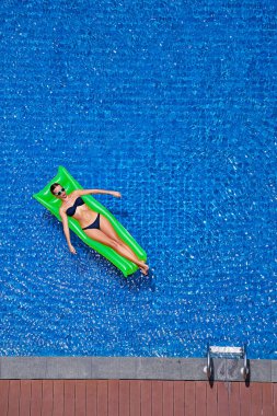 Büyük yüzme havuzunda yeşil şişme bikini ince genç kadının üstten görünüm.