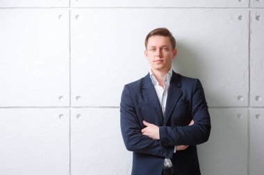 Geçti ve kamera duran beyaz duvara bakarak silah tutmak ceketli genç adam portresi.