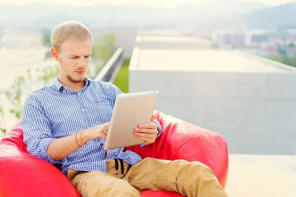 感兴趣的年轻人使用平板电脑 而坐在红豆袋 — 图库照片