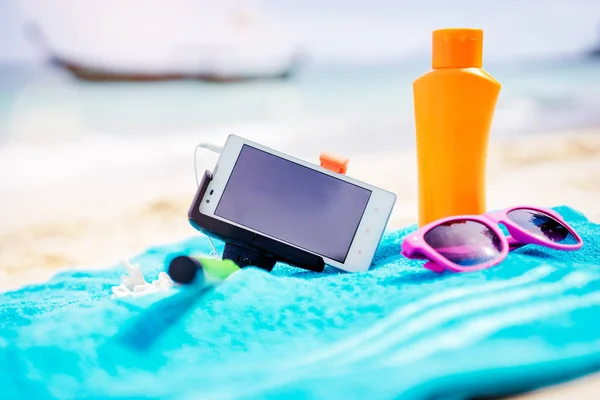 . Must have accessories on the sea beach. Smartphone, selfie stick, sunscreen and sunglasses.