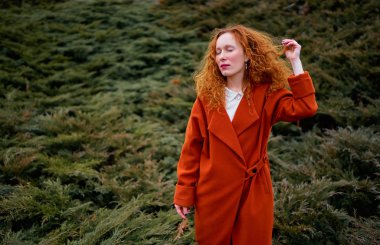 Turuncu bir palto giyiyor günlük Kızıl saçlı Genç güzel kadın portresi açık havada.