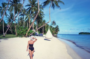 Genç kadının güzel tropikal beyaz kum plaj çekip arkadan görünüm.