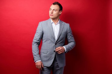 Kırmızı duvar karşı takım ayakta yakışıklı genç işadamı portresi.