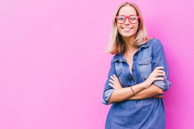 Renkli pembe duvara mutlu gülümseyen genç kadın portresi.