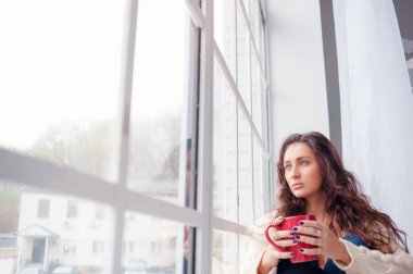 Pencerenin evde oturup çay olan güzel kadın.