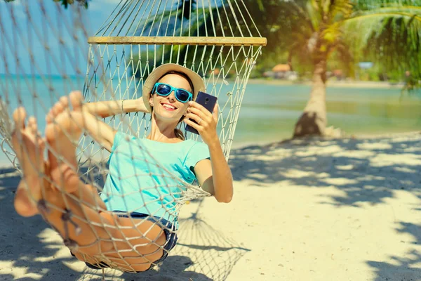 Mooie Jongedame Hoed Zonnebril Met Behulp Van Smartphone Tot Hangmat — Stockfoto