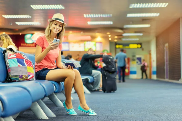 Młoda Kobieta Pomocą Smartfona Posiadających Bilety Siedząc Lotnisko Terminal Czeka — Zdjęcie stockowe