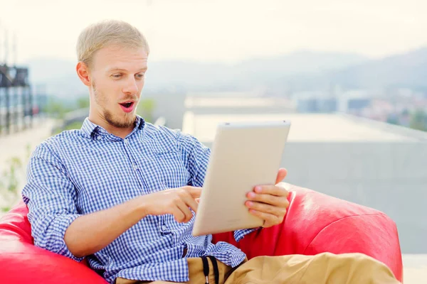 Hombre Joven Sorprendido Usando Tableta Mientras Está Sentado Bolsa Frijoles — Foto de Stock