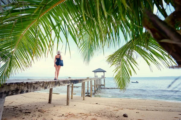 身着泳装和帽子的年轻女子站在木质沙滩码头上 — 图库照片