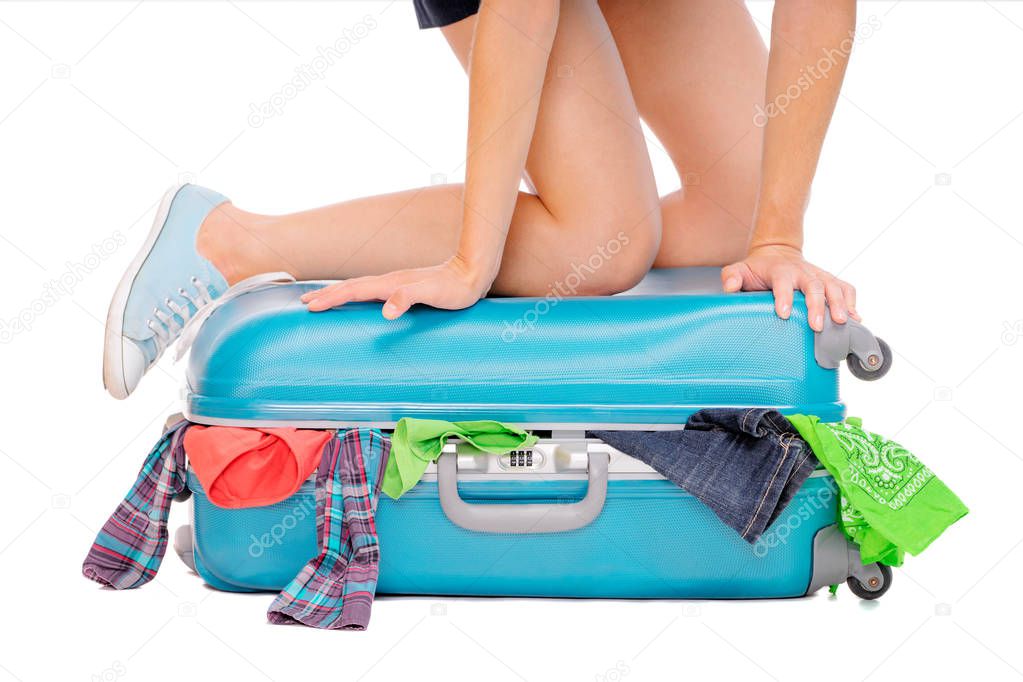 Woman trying to close her valise with cloth. Isolated on white.