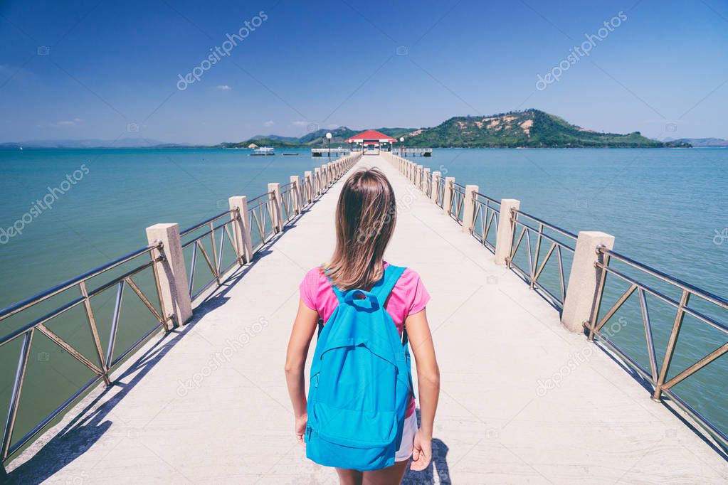 Young woman with rucksack walking on  jetty.