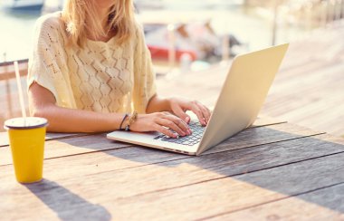 Dışarıda dizüstü bilgisayar kullanan genç bir kadın.