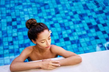 Güzel genç kadının resort yüzme havuzunda güneş.