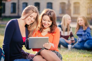 iki tablet pc bilgisayarlar bir çim üzerinde oturan ile gülümseyen genç kadın