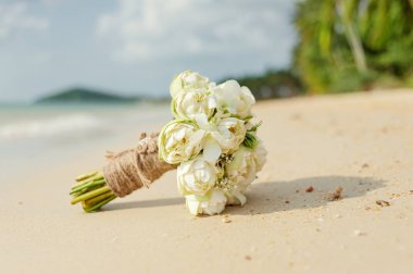 Güzel gelin buketi beyaz nilüferler ve tropikal bir plajda orkide