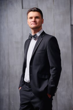 Smokin ve kravat takan yakışıklı genç adam portresi.