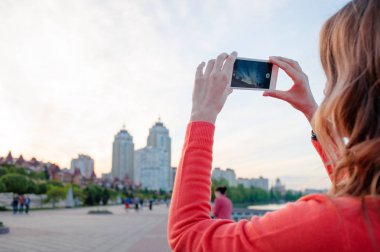 Smartphone'da city bölgesindeki yürürken fotoğrafta güzel saçlı genç kadın.