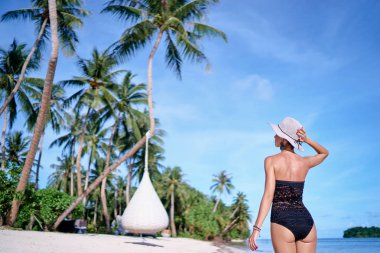 Genç kadının güzel tropikal beyaz kum plaj çekip arkadan görünüm.