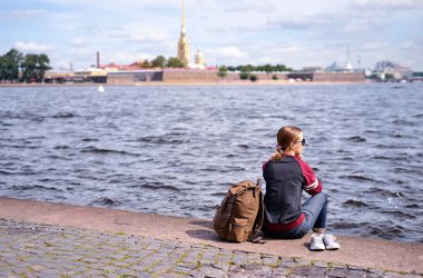 Peter ve Paul Kalesi, Saint Petersburg, Rusya Federasyonu manzarayı Neva Nehri'nin dolgu üzerinde oturan genç kadın.