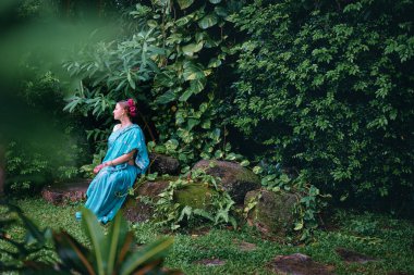 Güzel genç kafkas kadın geleneksel Hint kıyafetleri Sari Gelin Makyaj ve takı ve kına dövme yeşil bahçesinde otururken elleri ile.