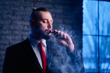 Yakışıklı genç adam Buharlaştırıcı Elektronik Sigara İçilmeyen takım elbise içinde sakallı.