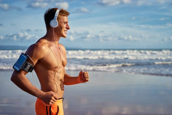 快乐的年轻人在耳机慢跑在海滨 — 图库照片