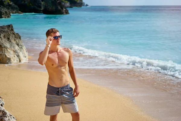 Portrait of young shirtless man on the sea beach.