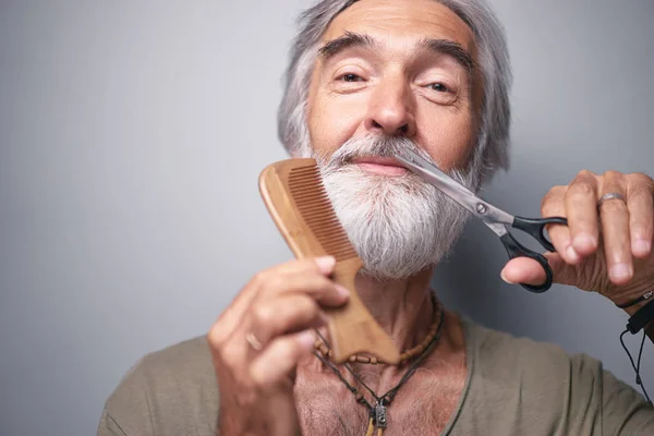 ハンサムな年配の男性彼のひげ近くはさみを押しカメラ目線 — ストック写真