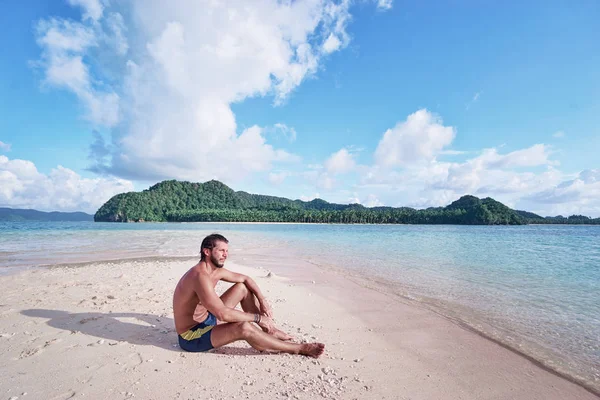 Zrelaksowany Młody Człowiek Siedzi Piaszczystej Plaży Ciesząc Się Widokiem Wyspę — Zdjęcie stockowe