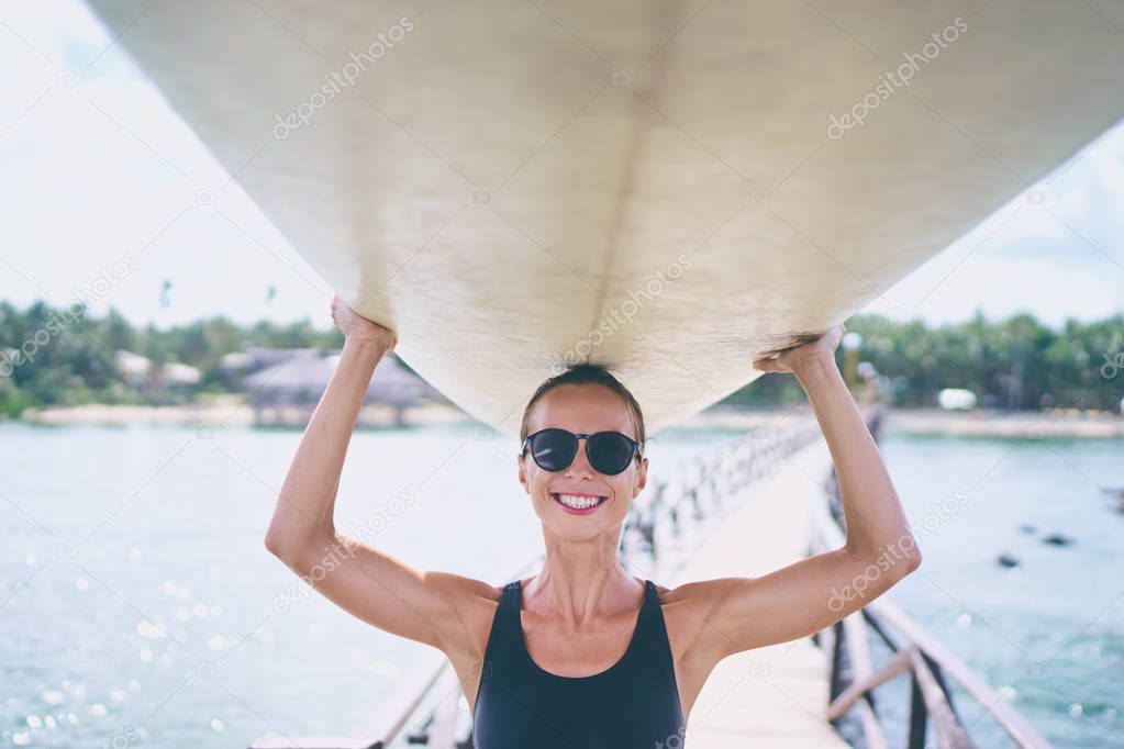 Pretty young woman carrying surf board.