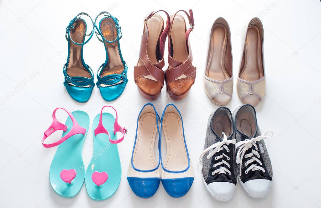 Different ladies shoes on white wooden background.