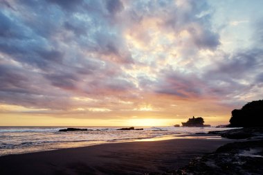  Antik Hinduizm Tapınağı Tanah lot bulutlu gökyüzü karşı kayaya. Bali Adası, Endonezya.
