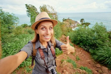 Şapka ve selfie denize yakın alarak sırt çantası olan kadın.