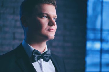 Smokin ve kravat takan yakışıklı genç adam portresi.