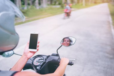 Motosiklet sürüş sırasında smartphone tutan kask içinde genç kadın. 