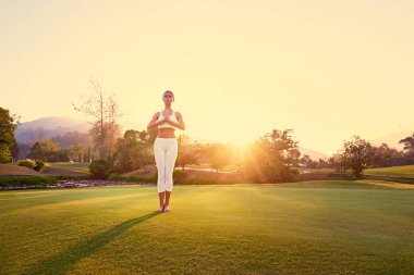 Asana genç kadın ayakta yeşil çimenlerin üzerinde poz. Sakin ve meditasyon kavramı.