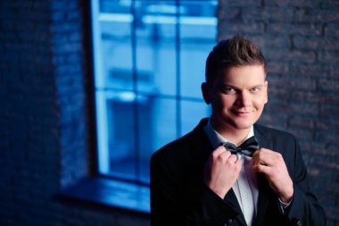 Smokin ve kravat takan yakışıklı genç adam portresi.