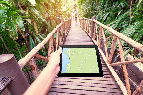 ジャングルの中で画面に地図とタブレット コンピューターを保持手のクローズ アップ — ストック写真