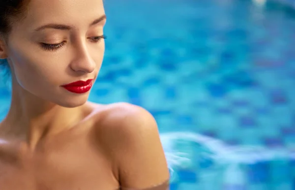 红色嘴唇化妆的美丽的年轻妇女在游泳池享受晒黑 — 图库照片