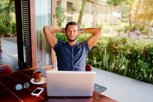 轻松的年轻胡子男子在膝上型电脑上工作 而坐在露台 — 图库照片