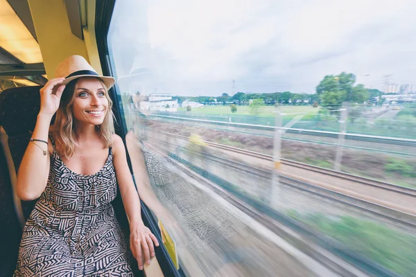 Young pretty woman traveling by the train sitting near the window.