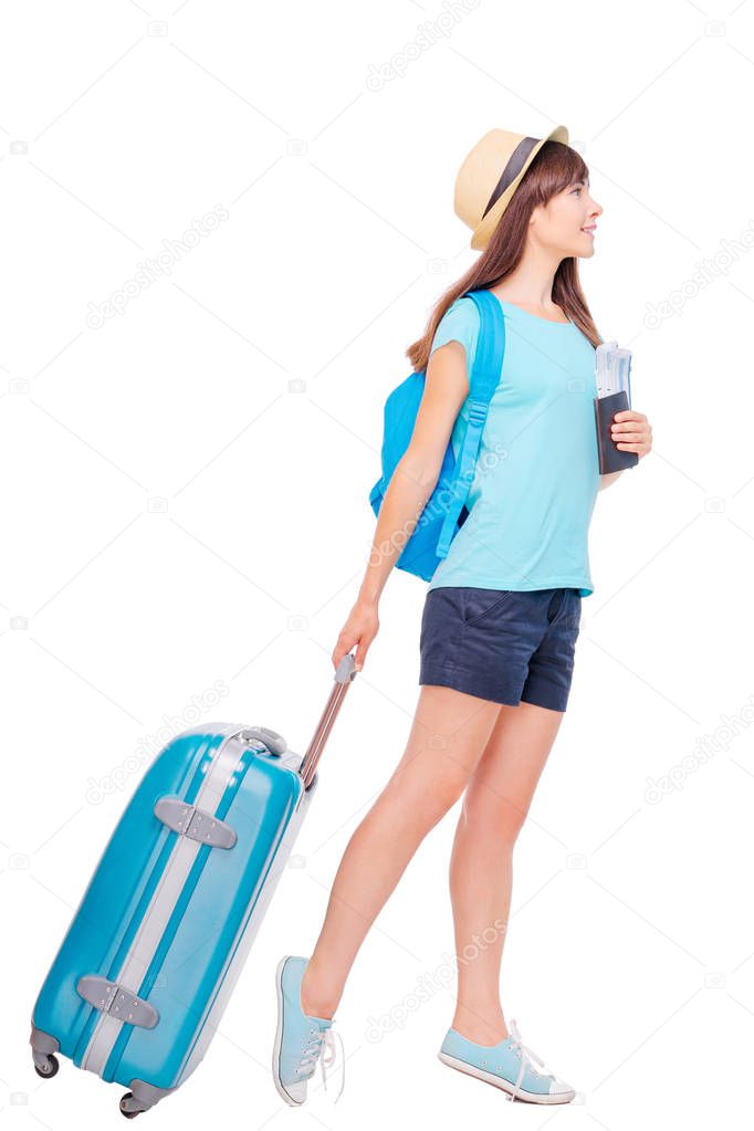 Full length studio portrait of pretty young woman holding passport with tickets walking with luggage
