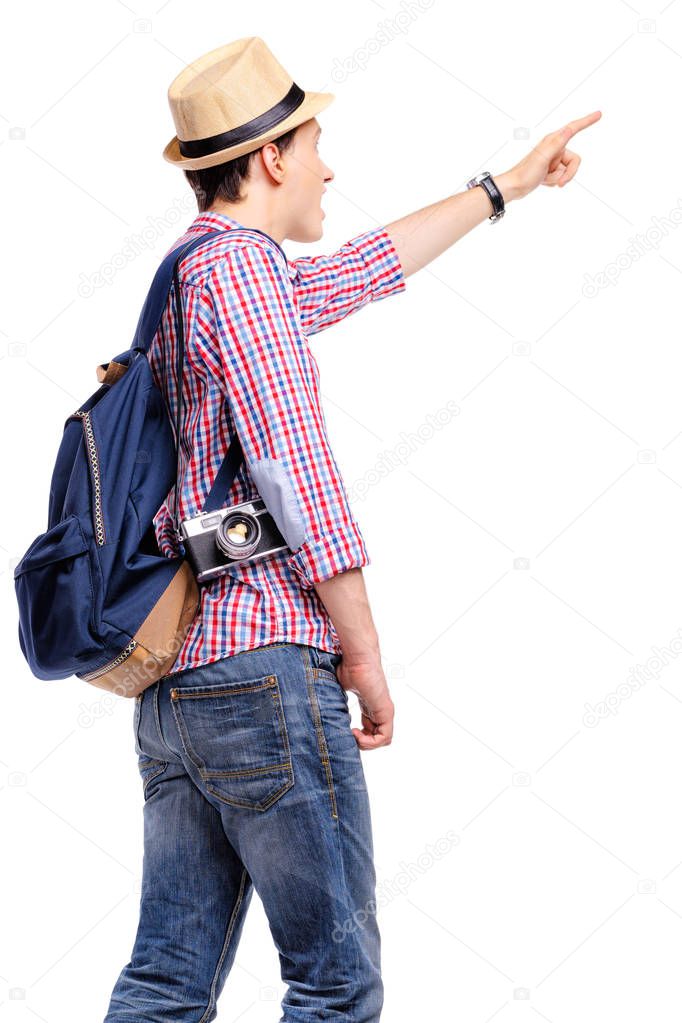 Travel concept. Studio portrait of young man in hat pointing away