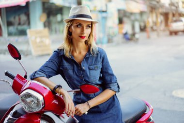 Açık kırmızı dudaklar makyaj şapka ayakta motobike yakınındaki olan genç ve güzel kadın portresi.