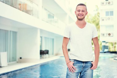 Mutlu genç adamın yanında yüzme havuzu.