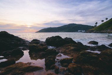 Deniz, taşlar ve günbatımı gökyüzü güzel manzaralı.