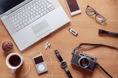 Farklı nesneler üzerinde ahşap arka plan. Öğeler içerir kamera, akıllı telefon, Gözlük, el feneri, dizüstü bilgisayar, izlemek, lastikbotlar, termos, fincan kahve, mp3 çalar