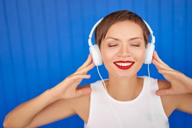 Renkli portre mutlu genç kadının beyaz kulaklık ile müzik dinleme.