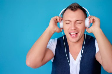 Renkli portre mutlu genç adamın beyaz kulaklık ile müzik dinleme.