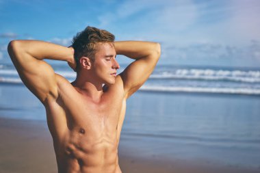 Yakışıklı ve güçlü bir genç adam plaj bronzlaşma.